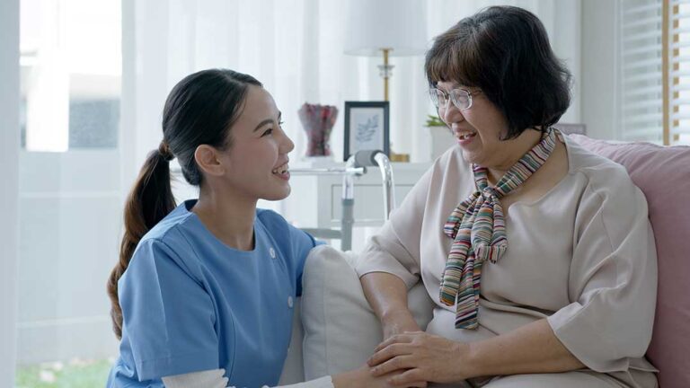 Care staff talking with an older adult while reviewing a personalized care plan in a comfortable residential setting.