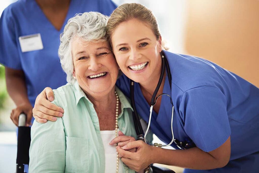 Older adult and family member reviewing a short-term assisted living room with a staff caregiver nearby.